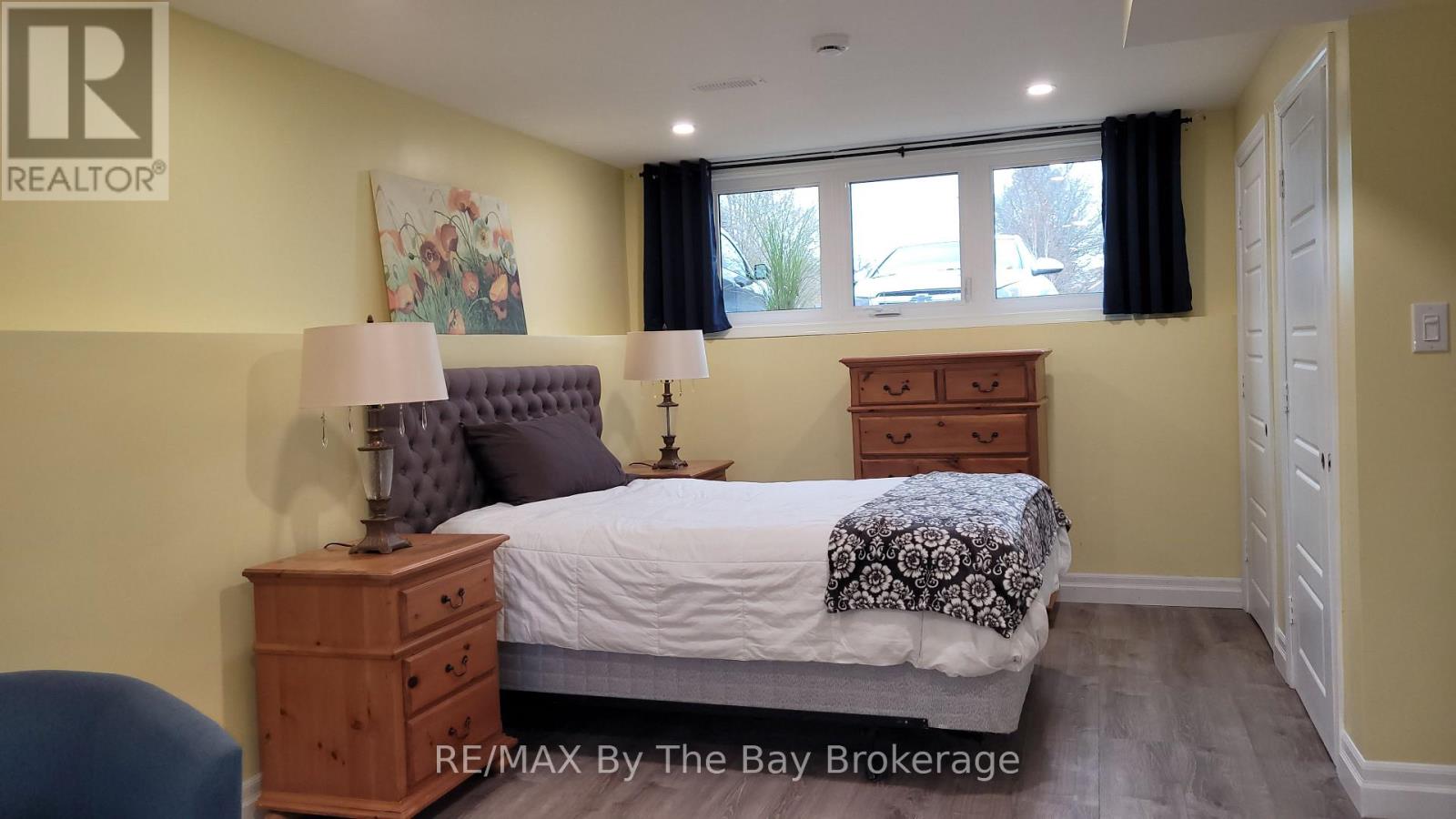 A bedroom with a bed, nightstand, and chair.