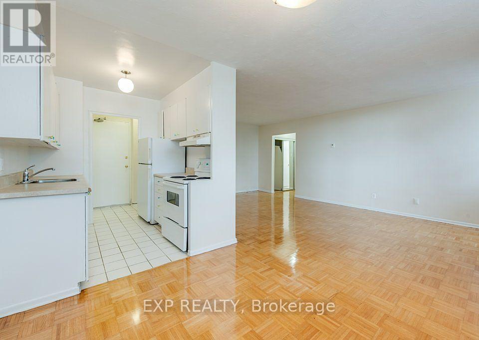 A kitchen with white cabinets and a wooden floor.