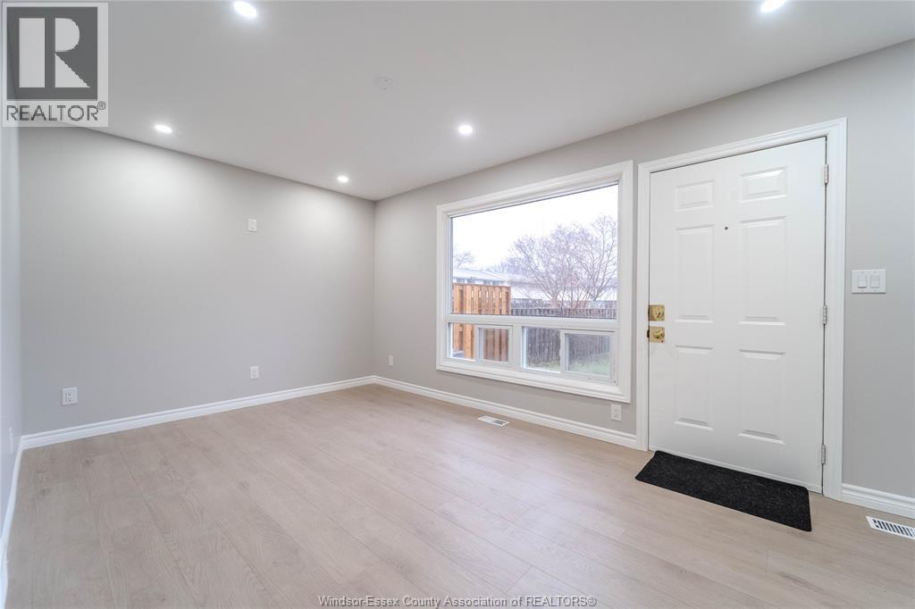 A room with a white door and a window showing a view of a building outside.