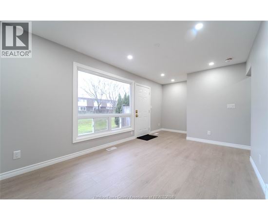 A spacious room with a large window and a door leading to a balcony.