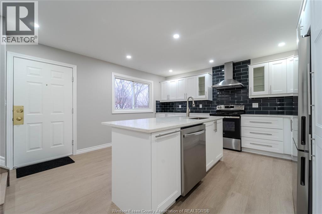 A kitchen with white cabinets and a black backsplash.