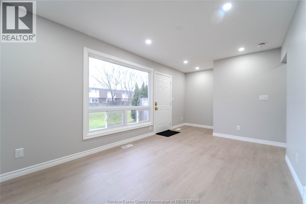 A spacious room with a large window and a door leading to a balcony.