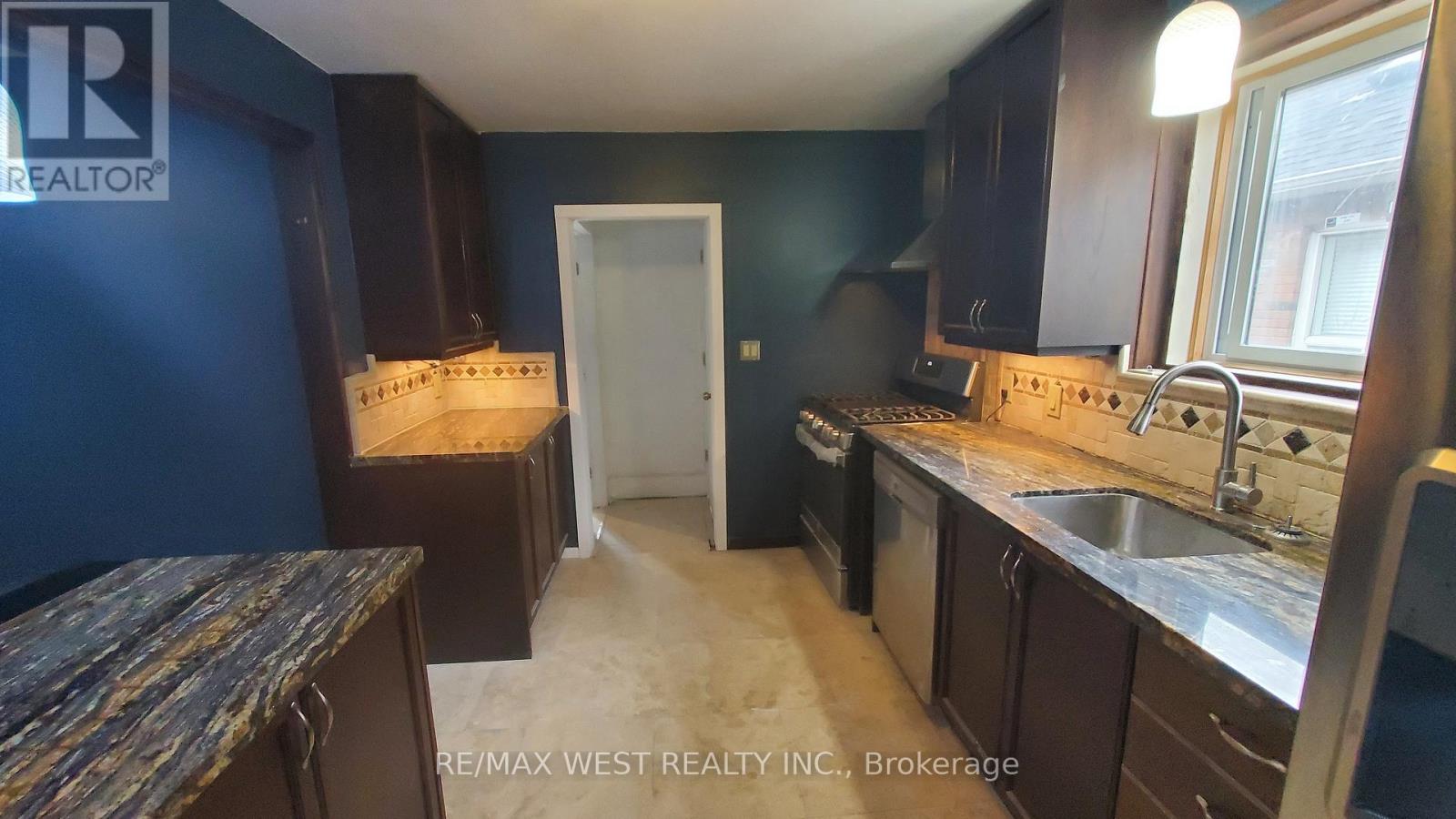 A kitchen with dark wood cabinets and a granite counter top.