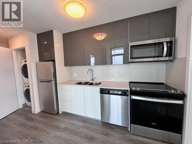 A modern kitchen with a stainless steel refrigerator, dishwasher, and oven.