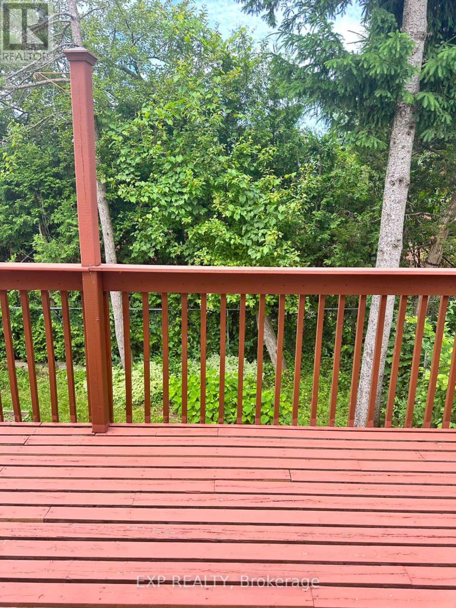 A red wooden deck with a railing and trees in the background.
