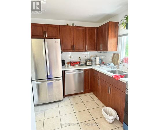 A kitchen with a stainless steel refrigerator and wooden cabinets.