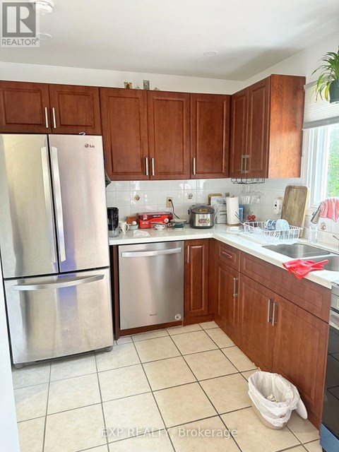 A kitchen with a stainless steel refrigerator and wooden cabinets.