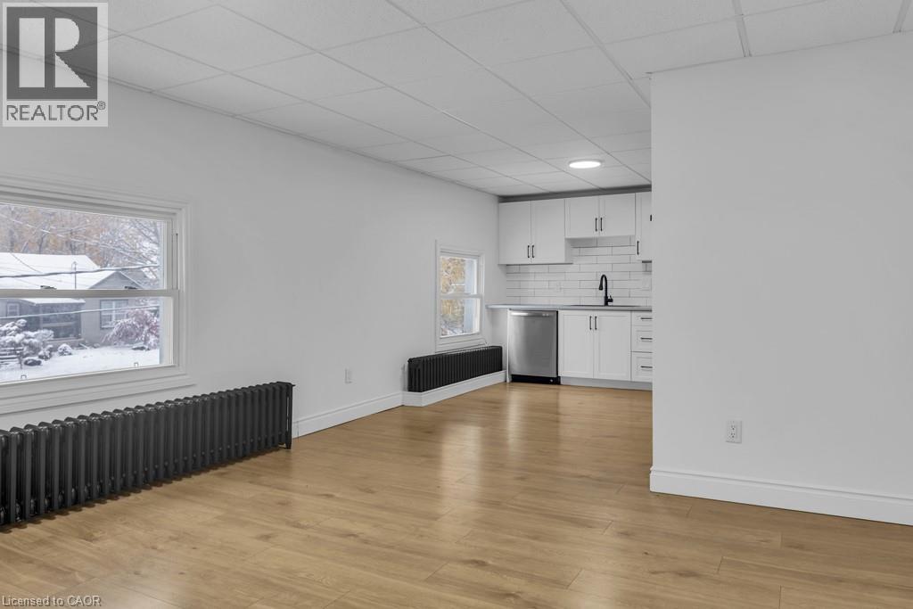 A spacious room with wooden flooring and a window showing a snowy landscape outside.
