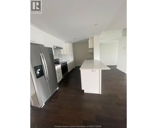 A kitchen with a stainless steel refrigerator and a white island.