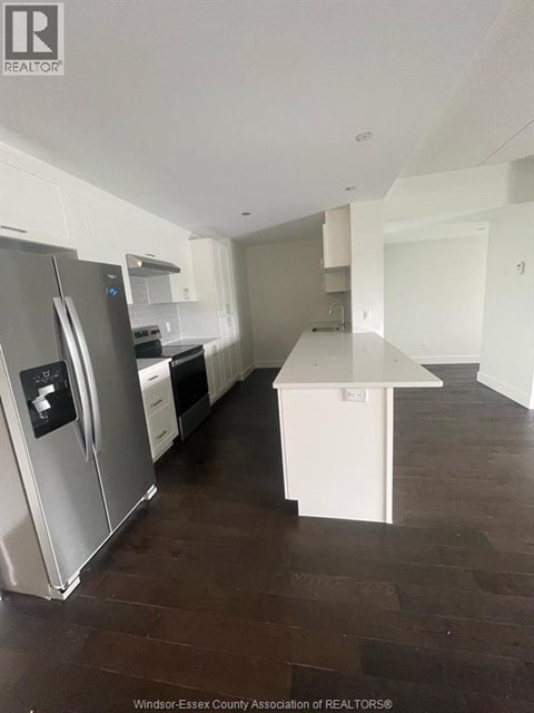 A kitchen with a stainless steel refrigerator and a white island.