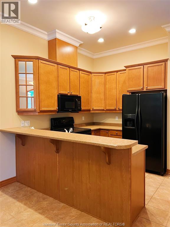 A kitchen with wooden cabinets and black appliances.