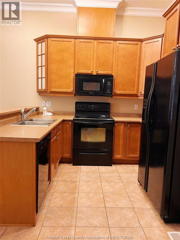 A kitchen with wooden cabinets and black appliances.