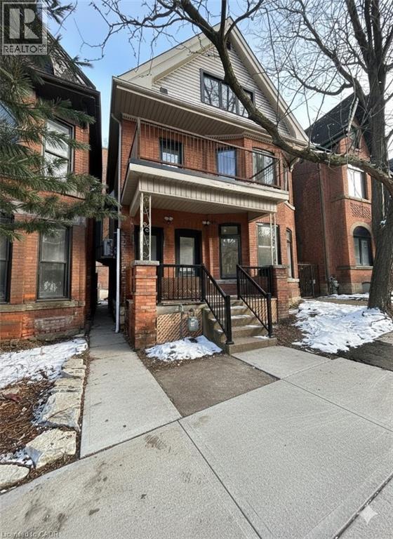 A house with a brown brick facade and a white porch.