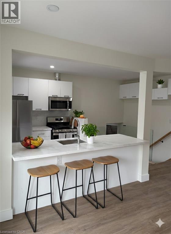 A kitchen with white countertops and wooden stools.