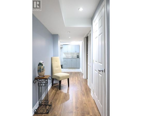 A hallway with a chair and a table with a vase on it.