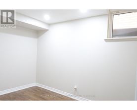 A white wall with a window and a wooden floor.