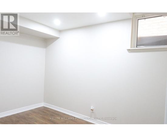 A white wall with a window and a wooden floor.