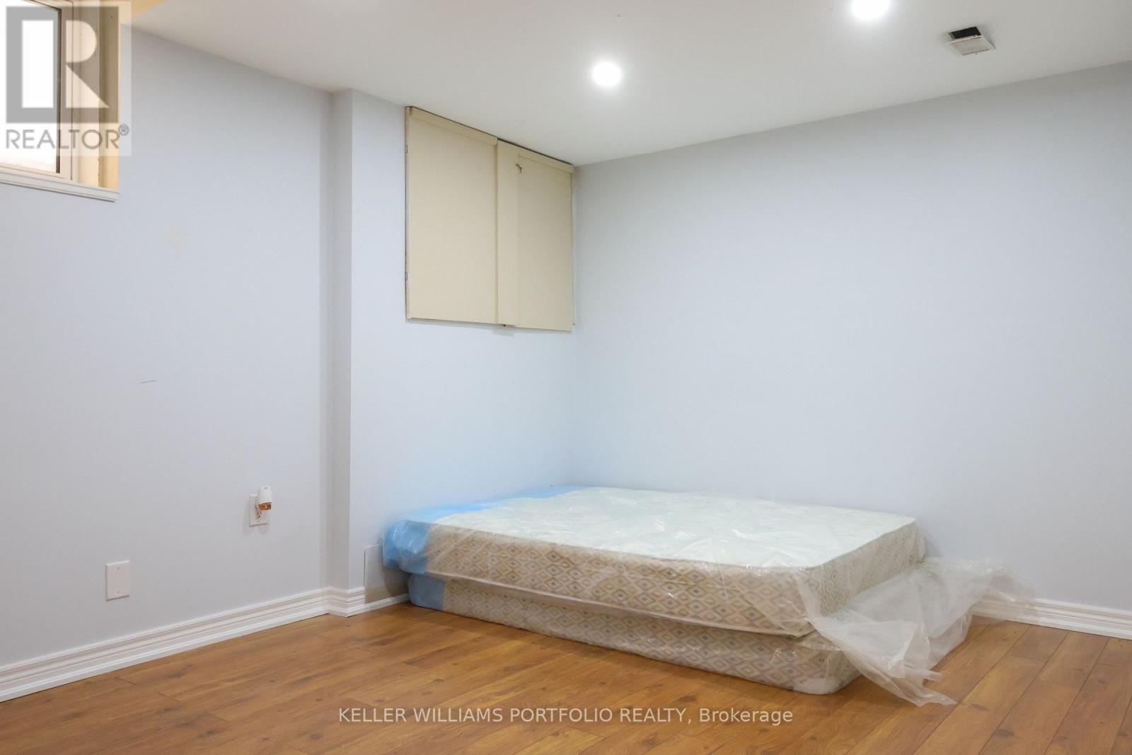 A bedroom with a bed covered in plastic and a white wall.