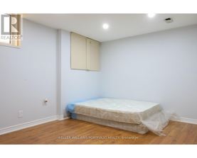 A bedroom with a bed covered in plastic and a white wall.