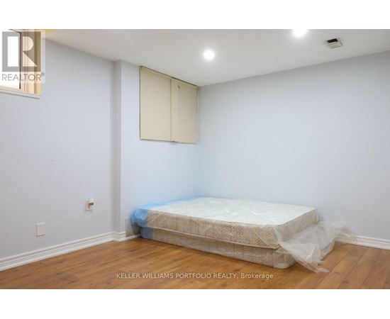 A bedroom with a bed covered in plastic and a white wall.