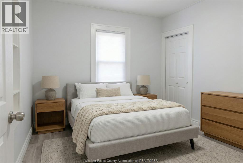A bedroom with a bed, two lamps, and a nightstand.