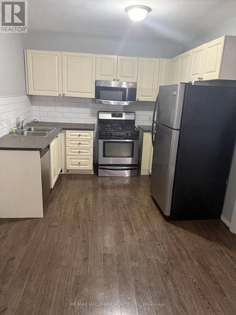 A kitchen with a black fridge and stove top oven.
