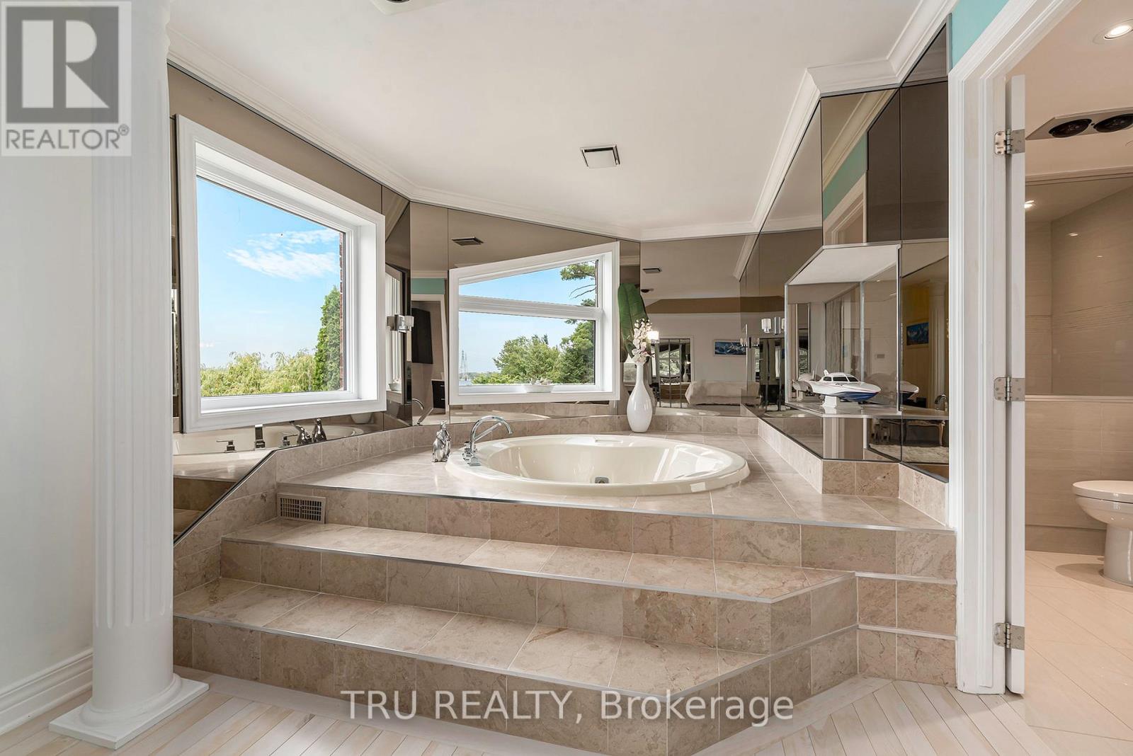 A bathroom with a large tub and a view of trees outside the window.