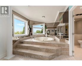 A bathroom with a large tub and a view of trees outside the window.