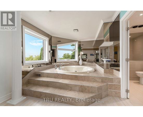 A bathroom with a large tub and a view of trees outside the window.
