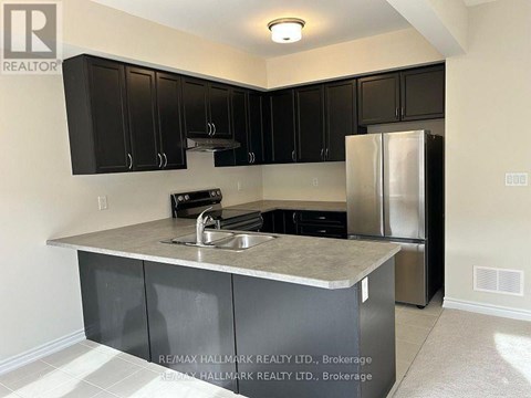 A kitchen with black cabinets and a stainless steel refrigerator.