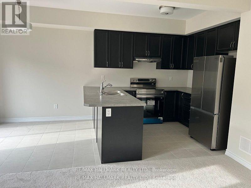 A kitchen with black cabinets and a stainless steel refrigerator.