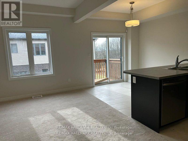 A large, empty room with a kitchen island and a window overlooking a deck.