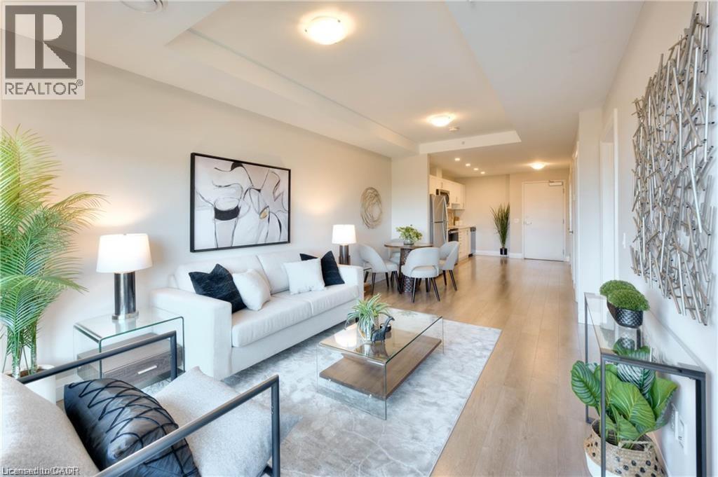 A well-lit, modern living room with a glass coffee table and a large abstract painting on the wall.