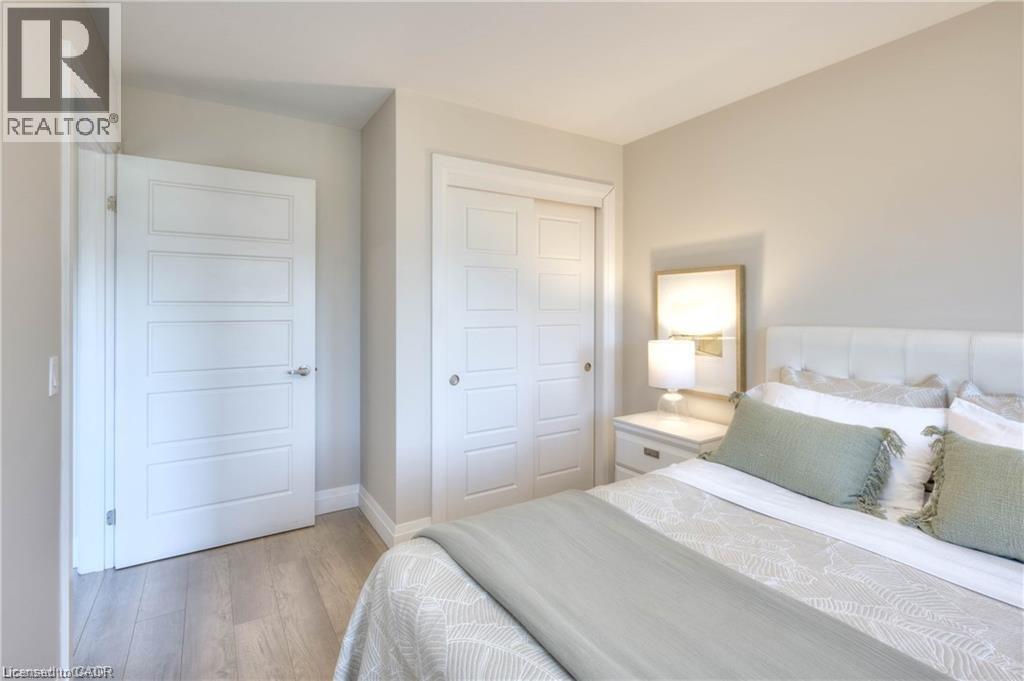 A bedroom with a bed, two doors, and a nightstand with a lamp.
