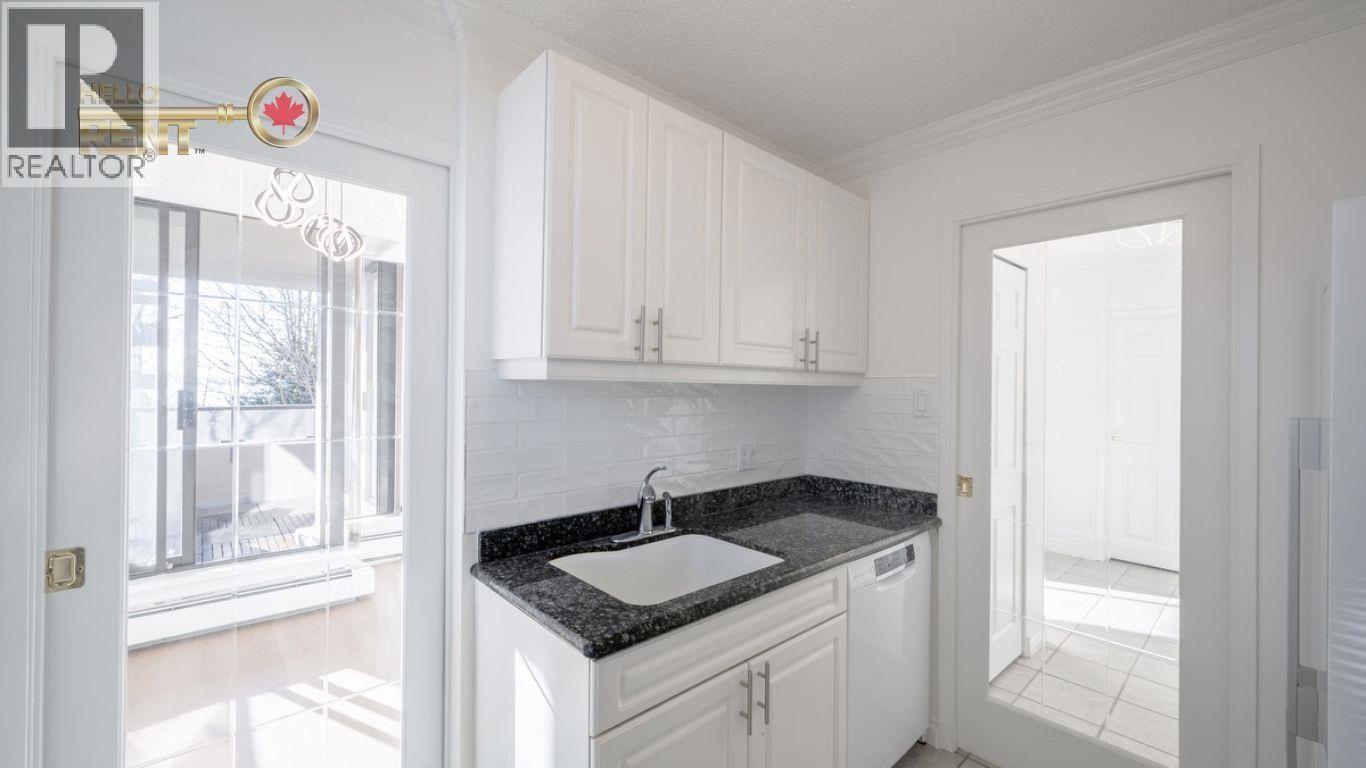 A white kitchen with a black counter top and cabinets.