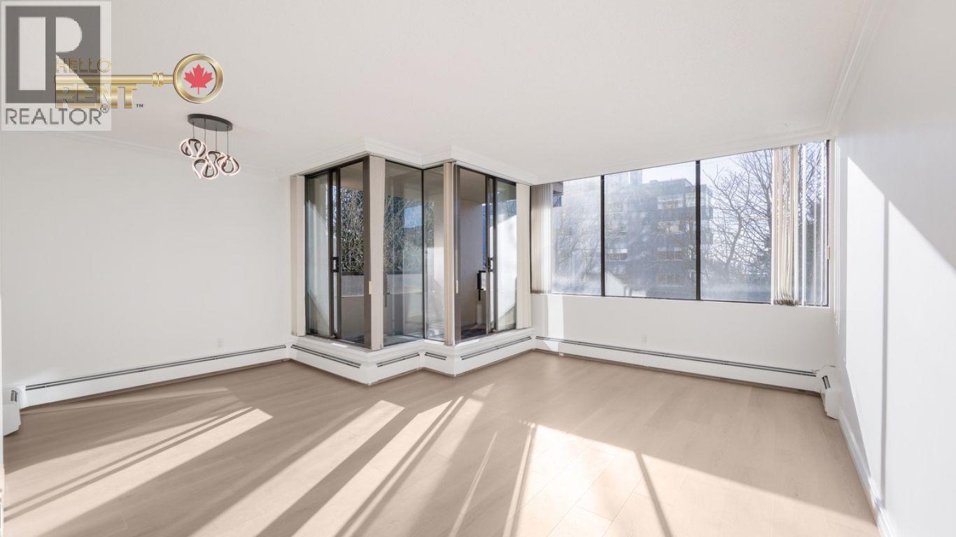 A spacious room with a large window and a wooden floor.