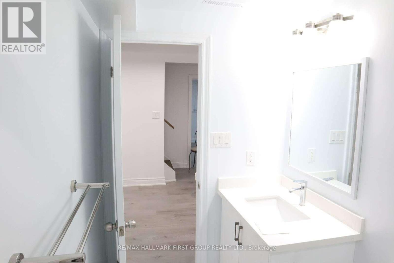 A bathroom with a sink, mirror and a door.