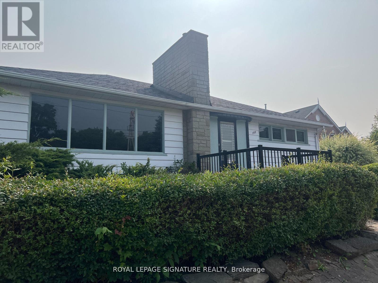 A white house with a black fence and a sign that says Royal LePage Signature Realty, Brokerage.