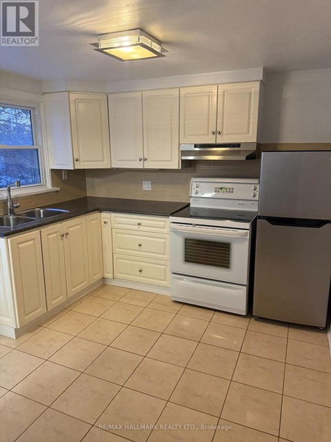 A kitchen with white cabinets and a black fridge.