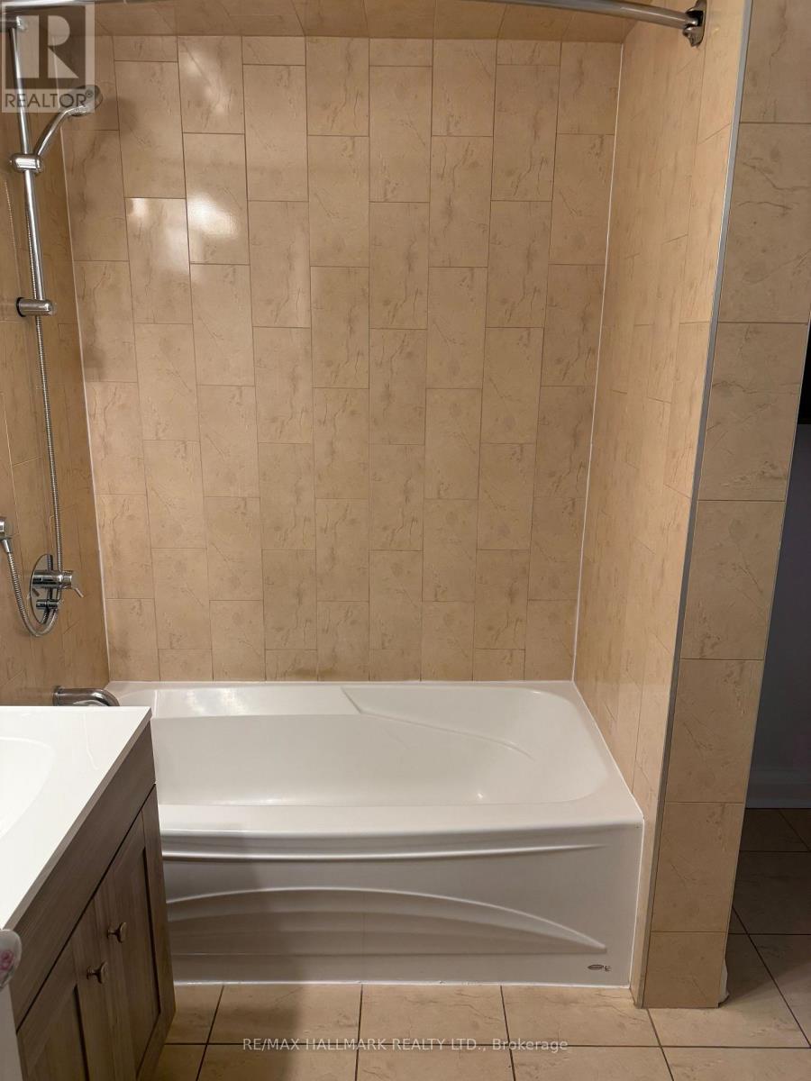 A white bathtub in a bathroom with beige tiled walls.