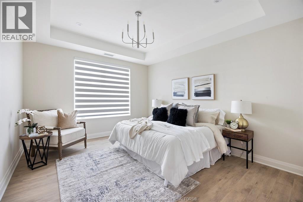 A bedroom with a large bed, a chair, and a table with a lamp on it.
