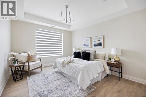A bedroom with a large bed, a chair, and a table with a lamp on it.