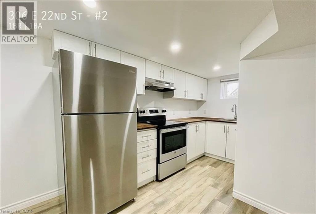 A modern kitchen with a stainless steel refrigerator and white cabinets.