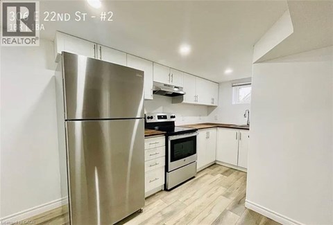 A modern kitchen with a stainless steel refrigerator and white cabinets.