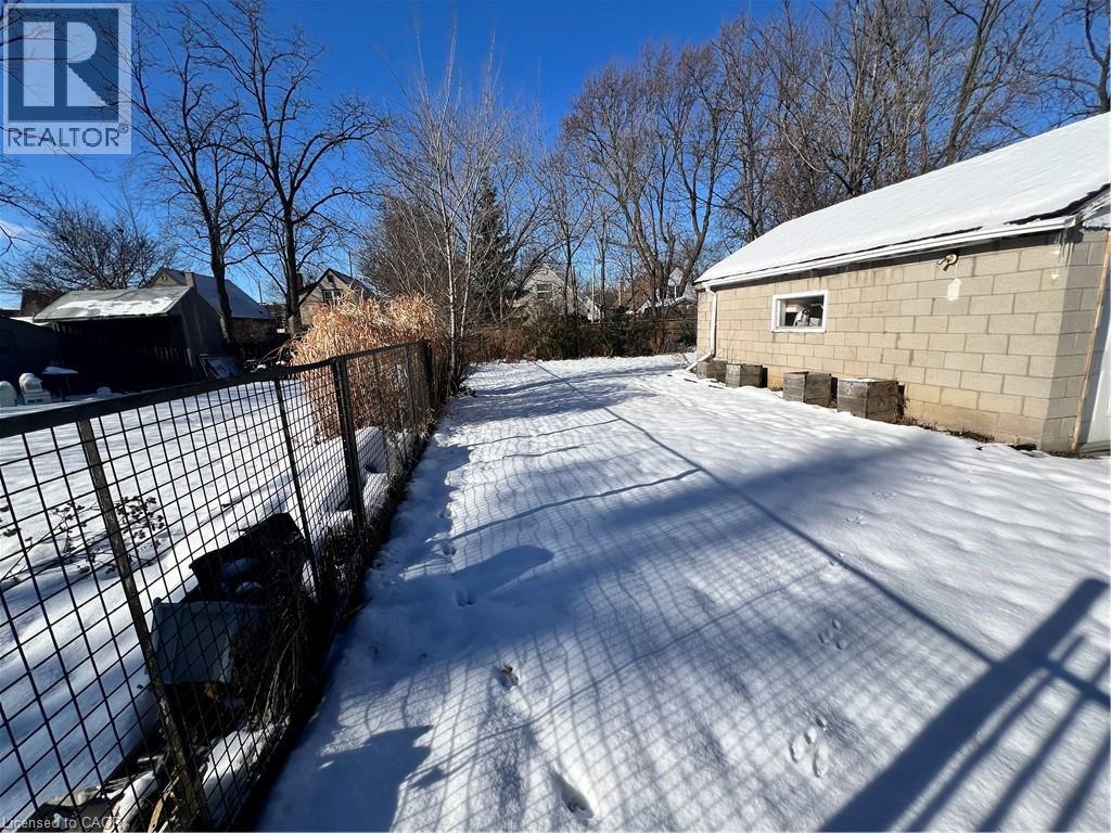 A snow-covered yard with a fence and a building in the background.
