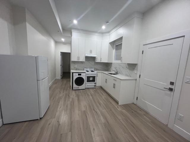 A kitchen with white cabinets and a washer and dryer in it.