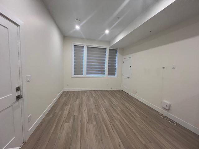 A room with wooden flooring and a window with blinds.