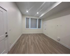 A room with wooden flooring and a window with blinds.