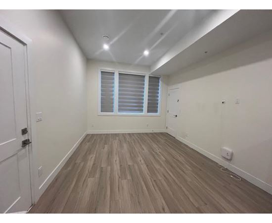 A room with wooden flooring and a window with blinds.