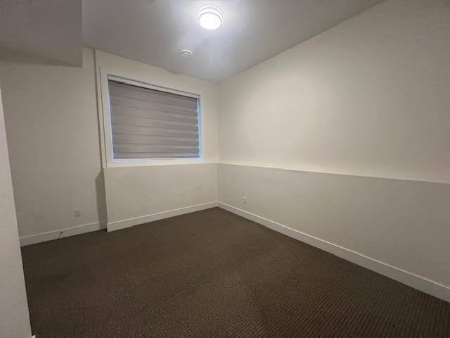 A room with a carpeted floor and a window with blinds.